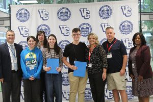 principal Russel burns (left) and superintendent Evette Avila (right) pose with National Merit Scholarship Semifinalists Connor Walsh and Amelia Krouse and their family members.