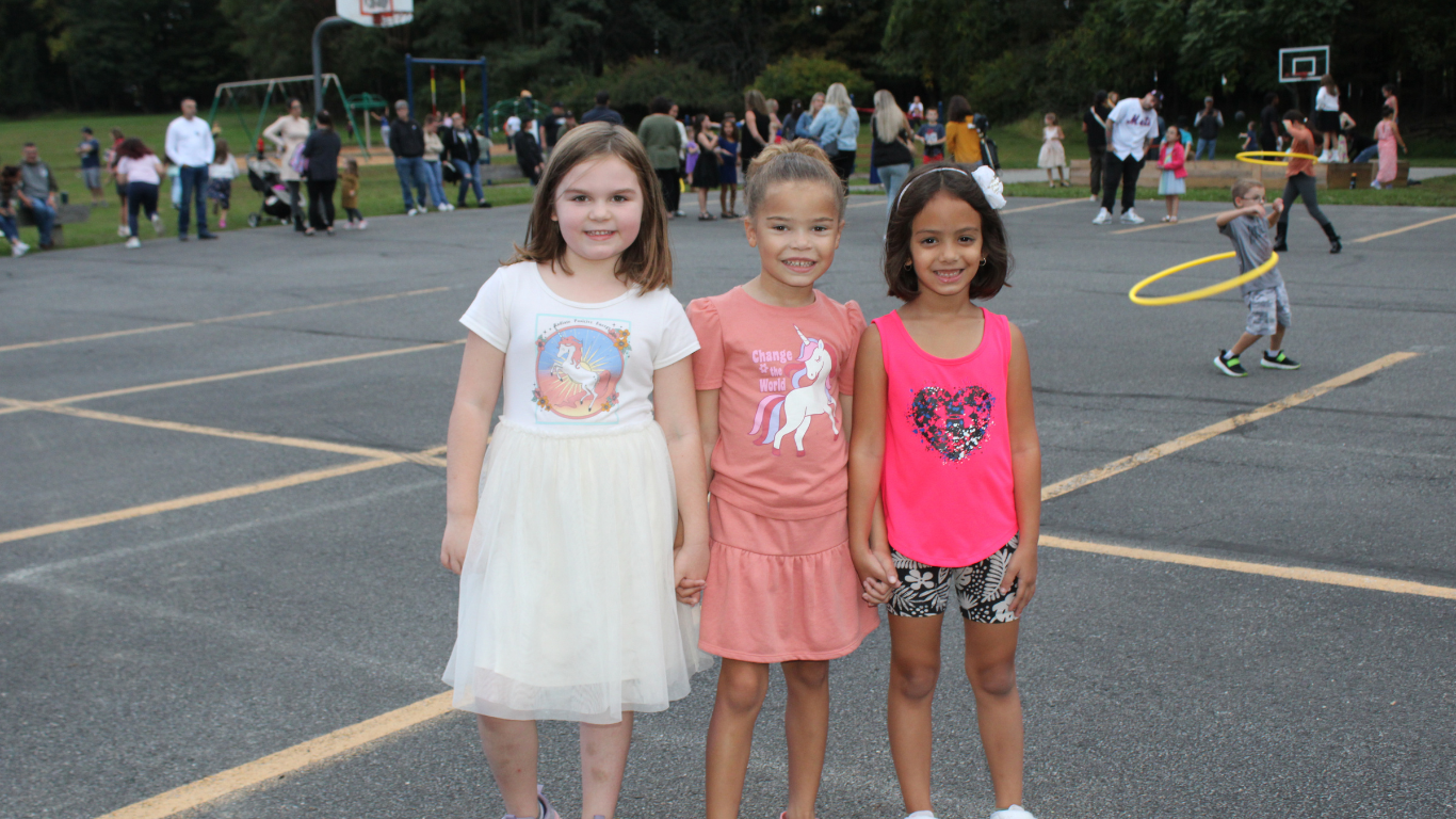 Three girls standing and smiling on the MES playground.