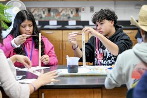 Two students measuring liquid into a beaker.