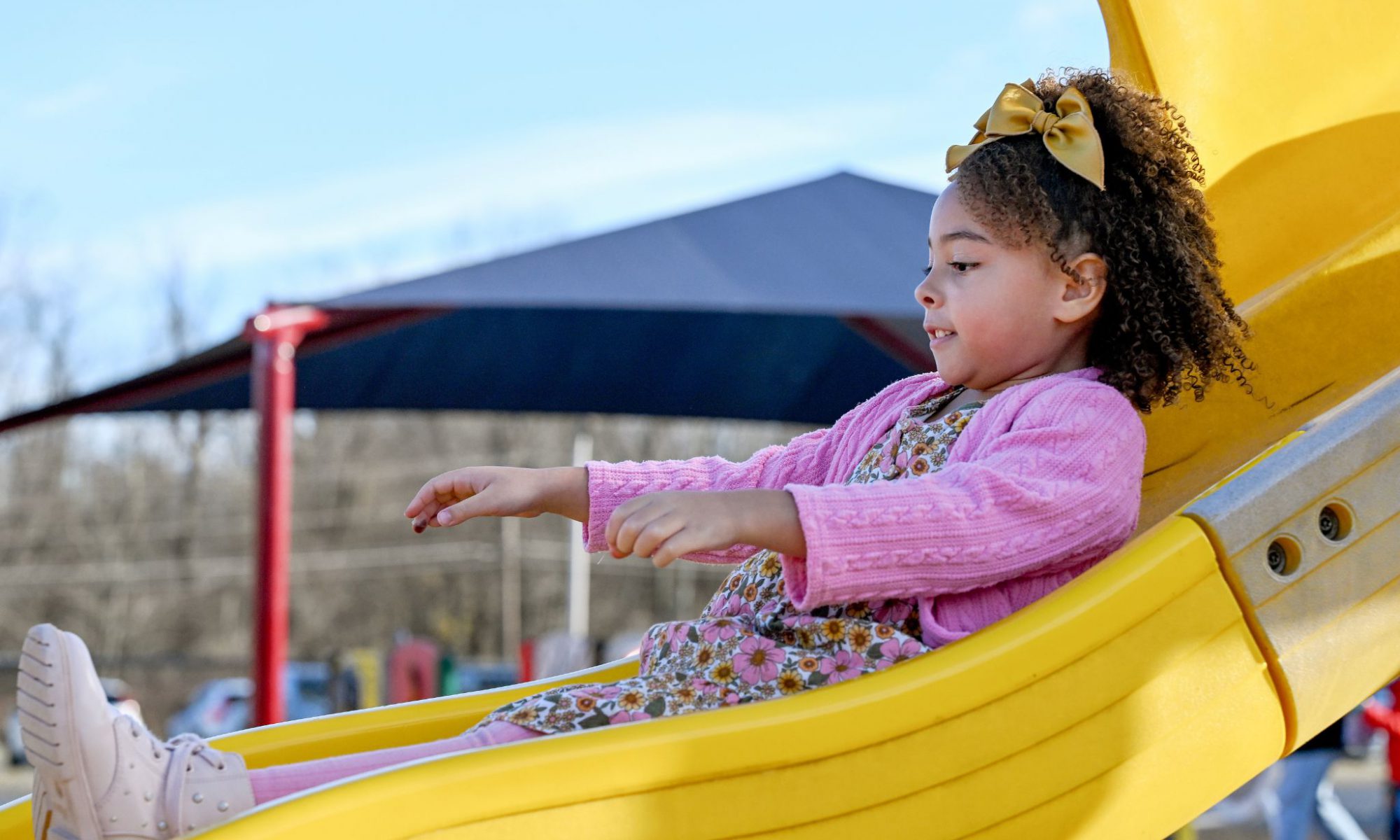 A student goes down the slide at the playground.