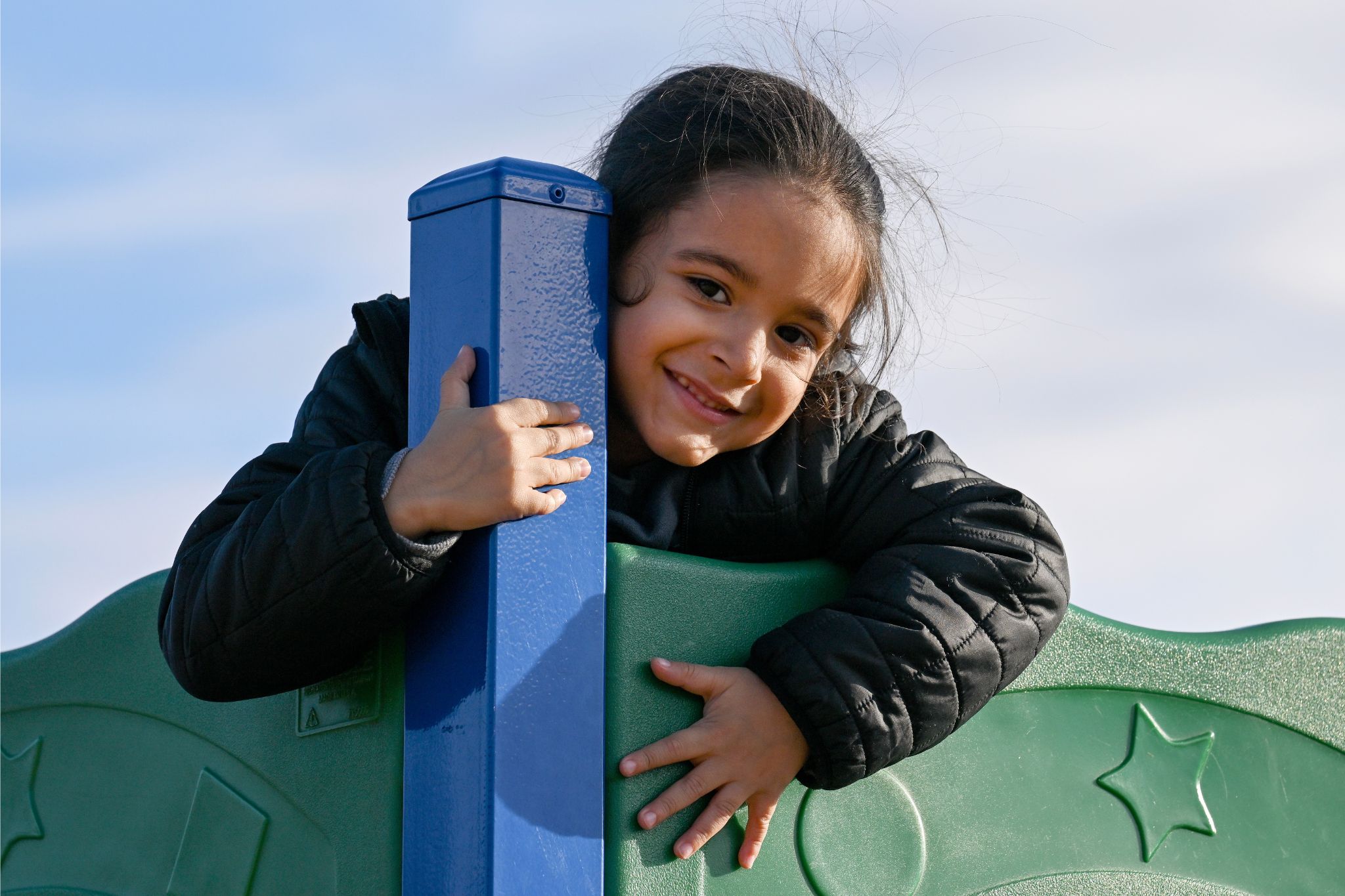 A student smiles for the camera on the playground from the top of a play area.