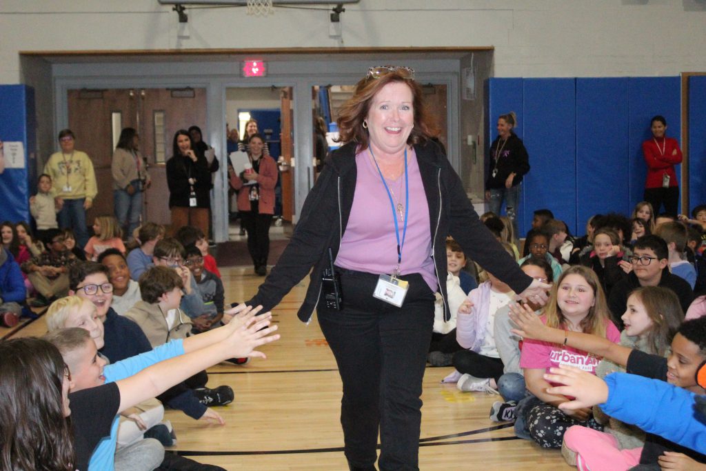  Patricia Crowley, a paraprofessional at Walden Elementary School, receives high fives from students as she is called up to the front of the room to receive recognition during a PBIS assembly. 
